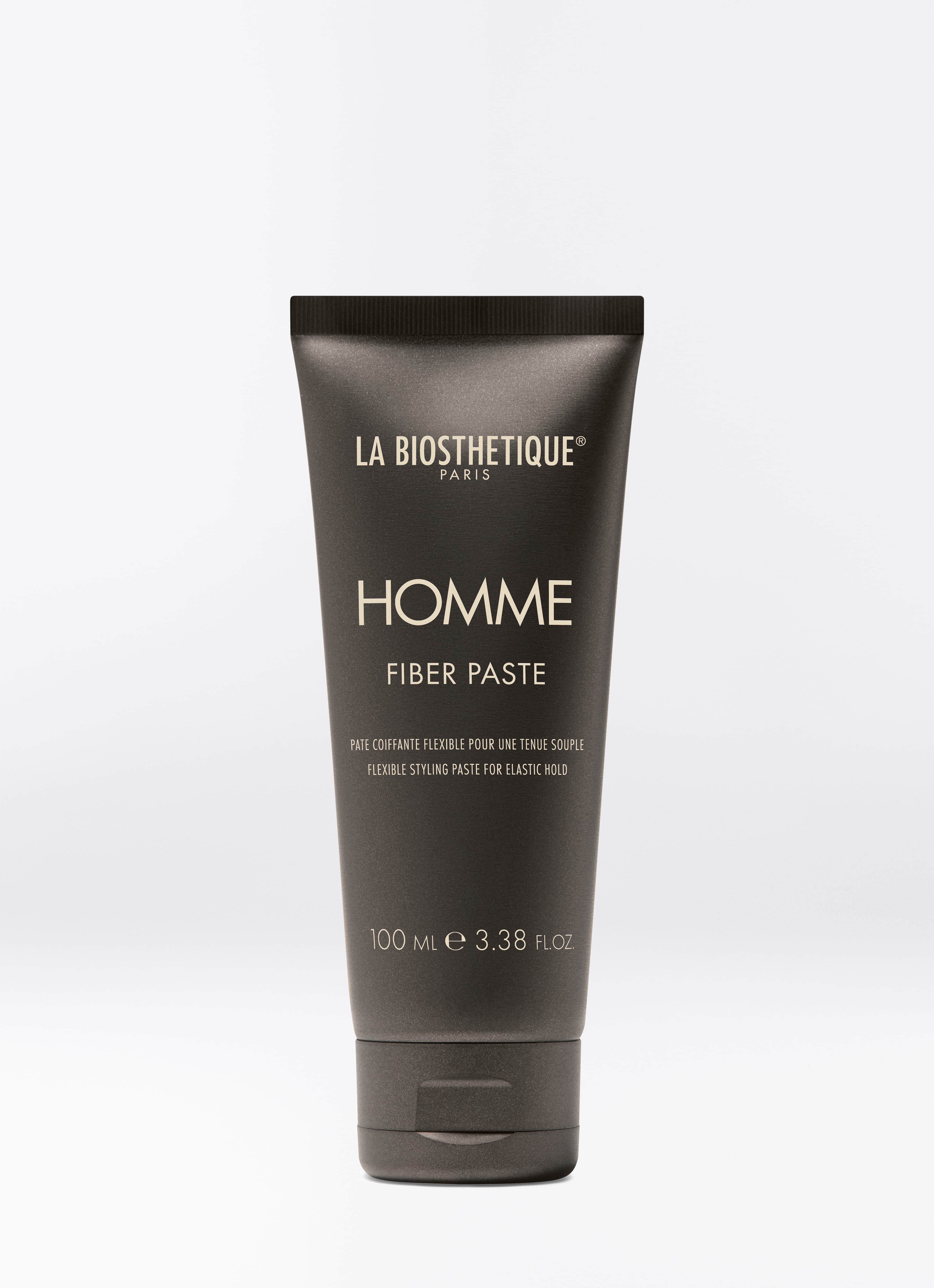Dunkelbraune Tube des Homme Styling Gel auf hellgrauem Hintergrund.