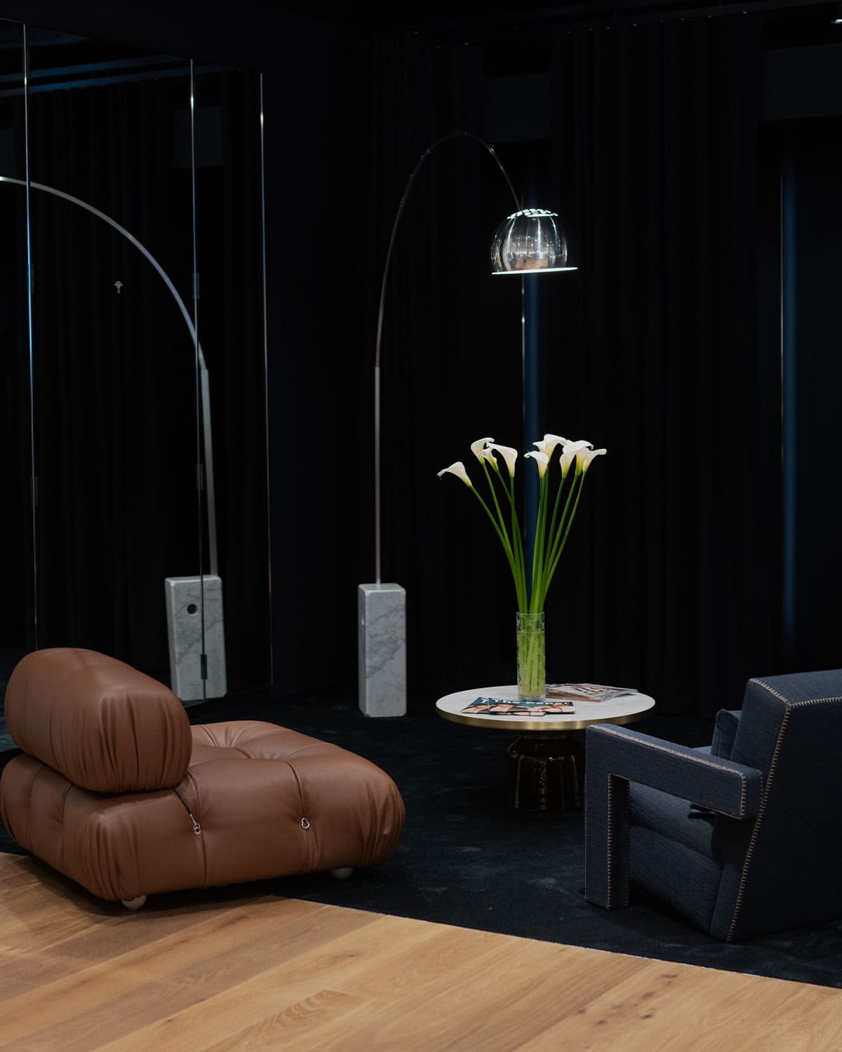 JOOP! store with gray leather armchair in front of a dark dressing room with a small side table with flowers 