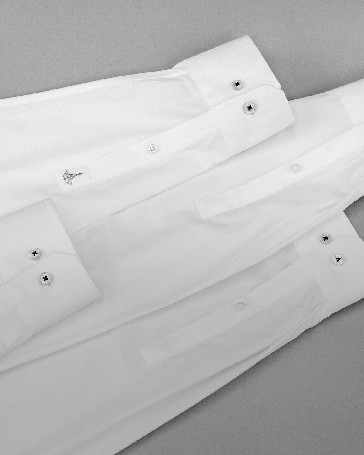 four white shirt sleeves on a gray table