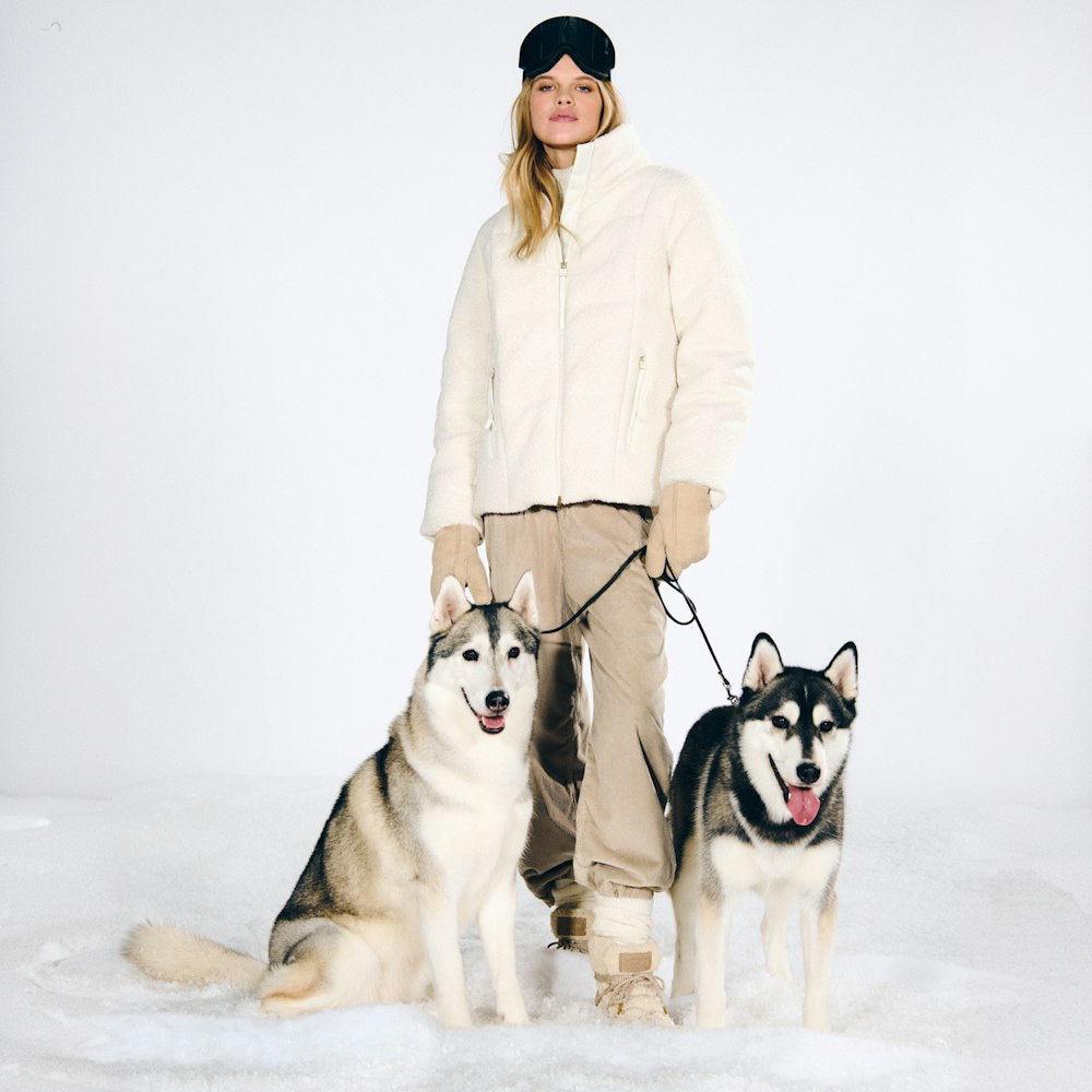 JOOP! Woman in cream winter jacket with huskies in the snow