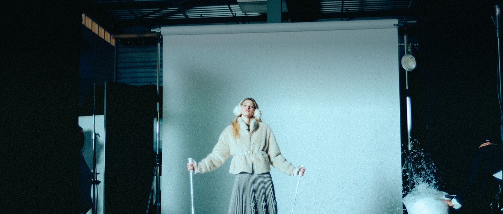 JOOP! Behind the Scenes — Woman in cream quilted jacket with pleated skirt in front of a projection screen