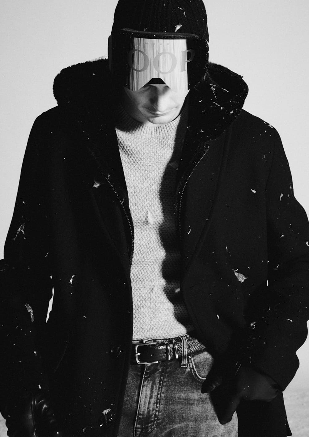 Joop, a man wearing a light gray sweater, a black coat, and gray jeans