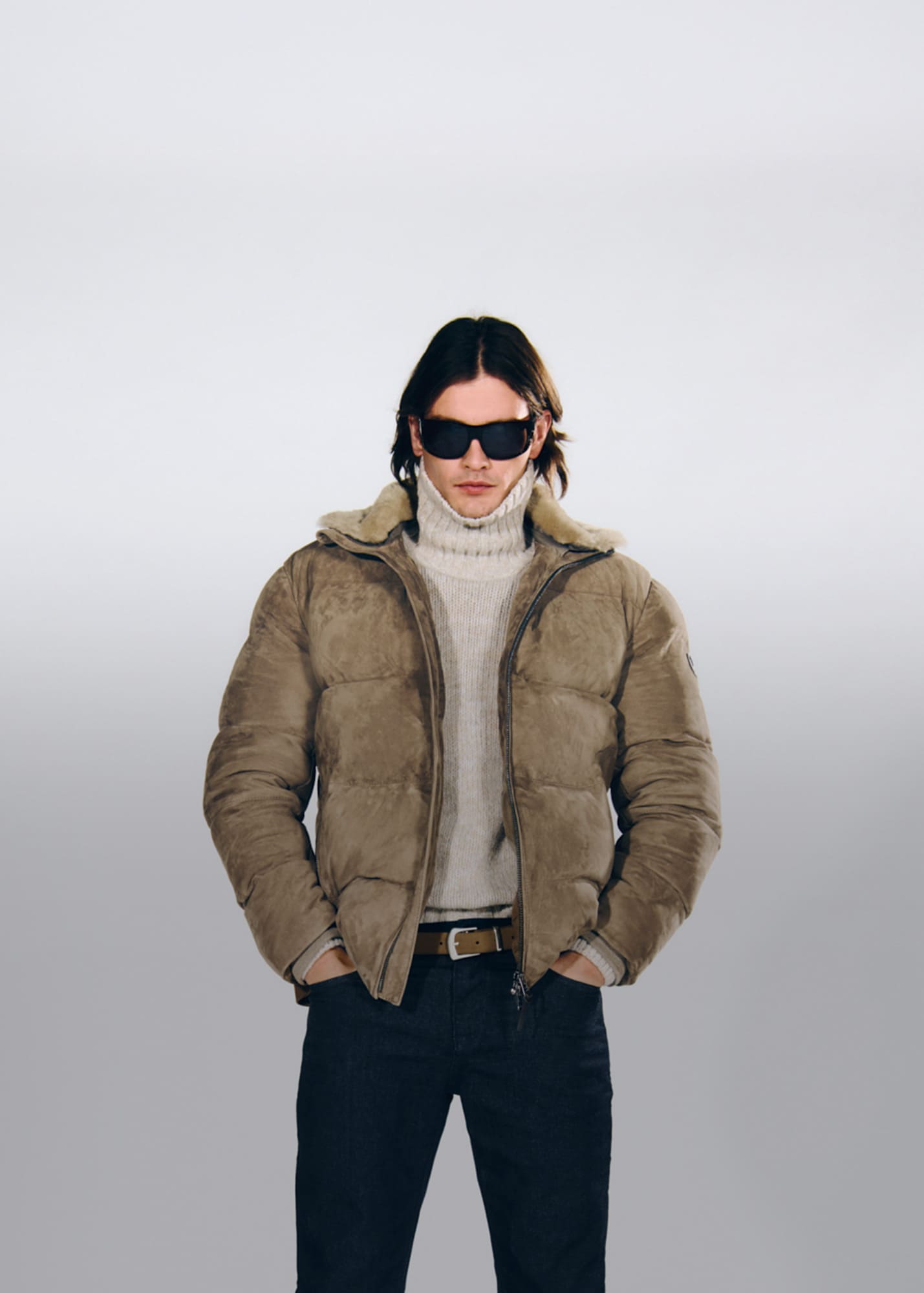 Joop, a man wearing a brown lined jacket, a cream-colored turtleneck sweater, and jeans