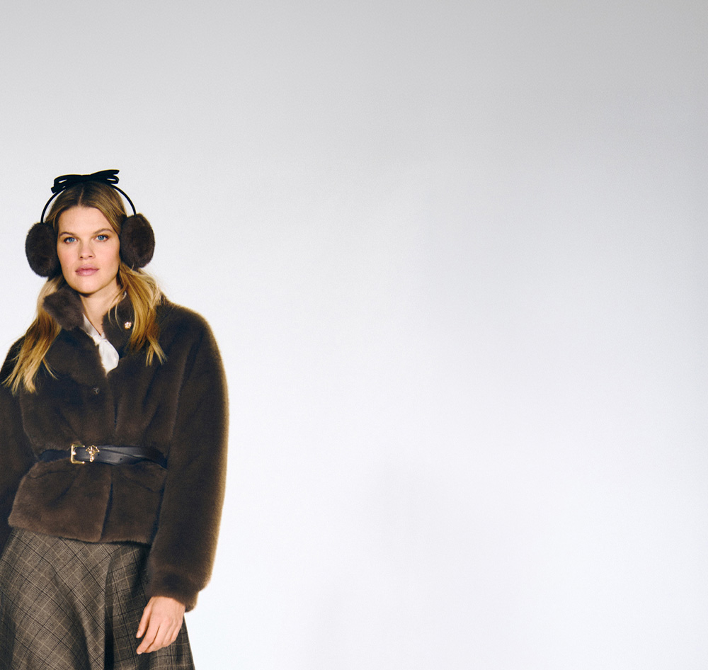 Woman wearing a brown Joop faux fur short jacket with a brown plaid skirt