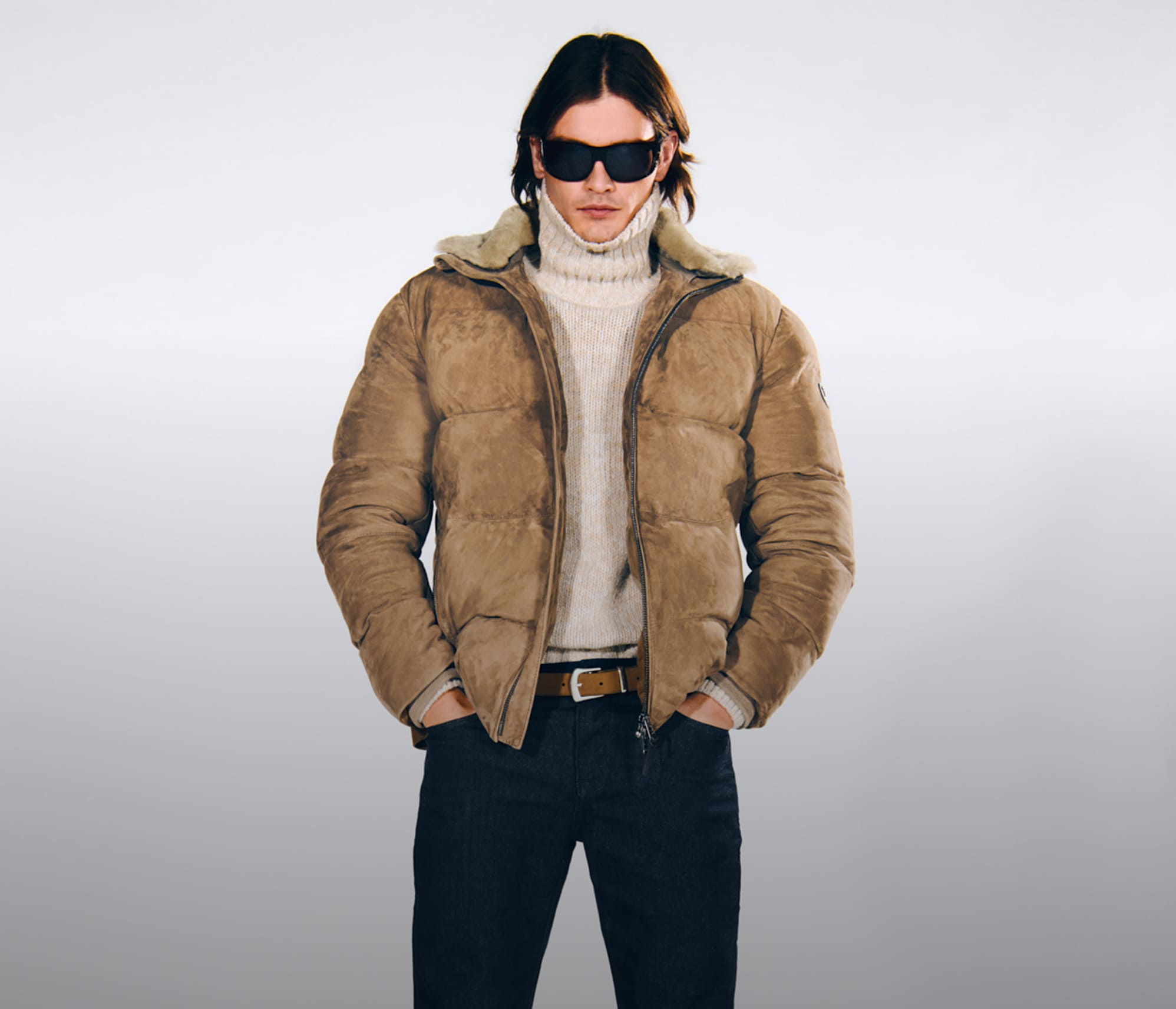 Joop, a man wearing a brown lined jacket, a cream-colored turtleneck sweater, and jeans