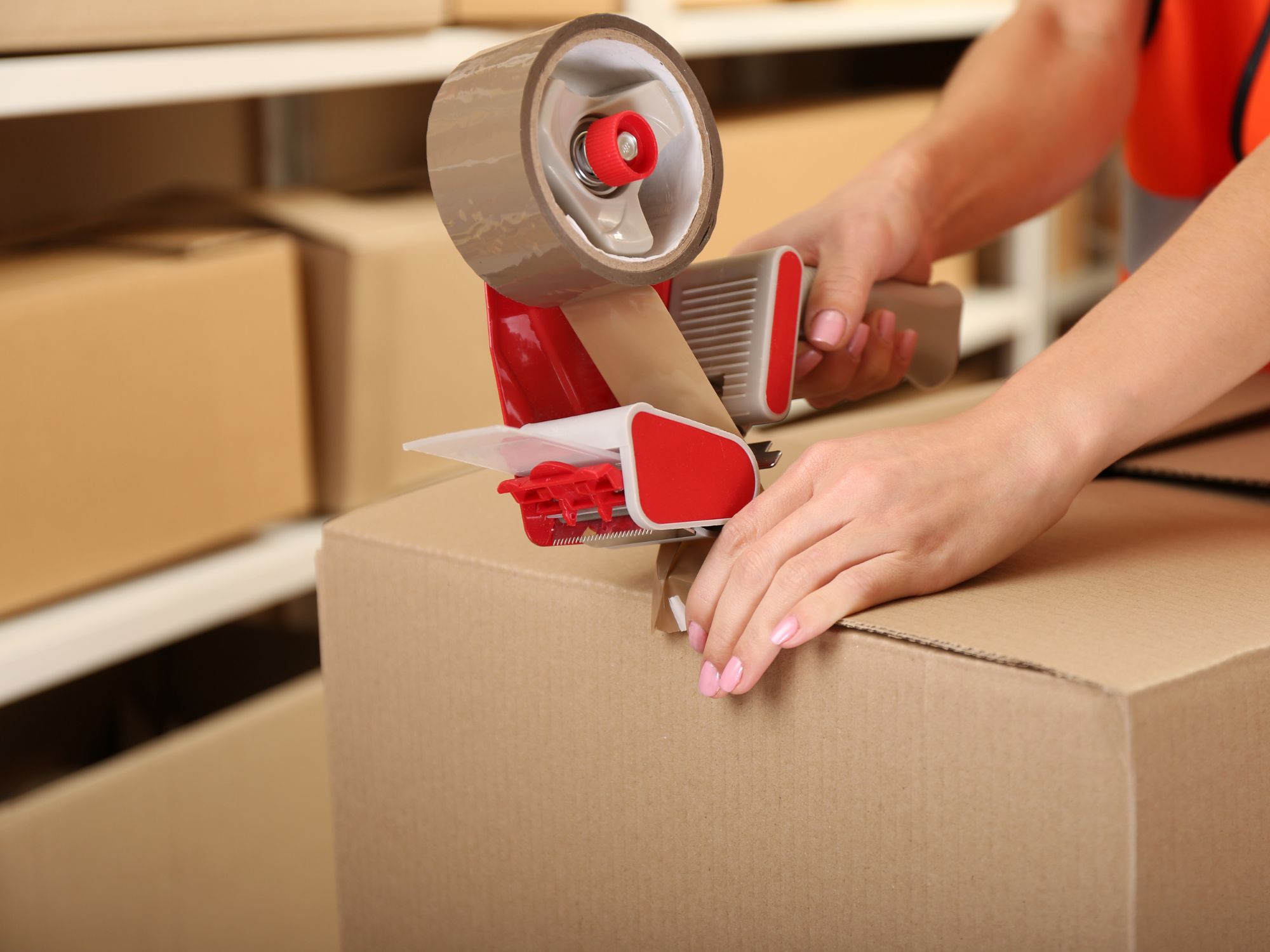 Fachkraft Lagerlogistik schliesst Paket mit Klebeband