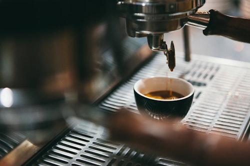 Het espresso som droppar ned i en espressokopp från en italiensk kaffemaskin.
