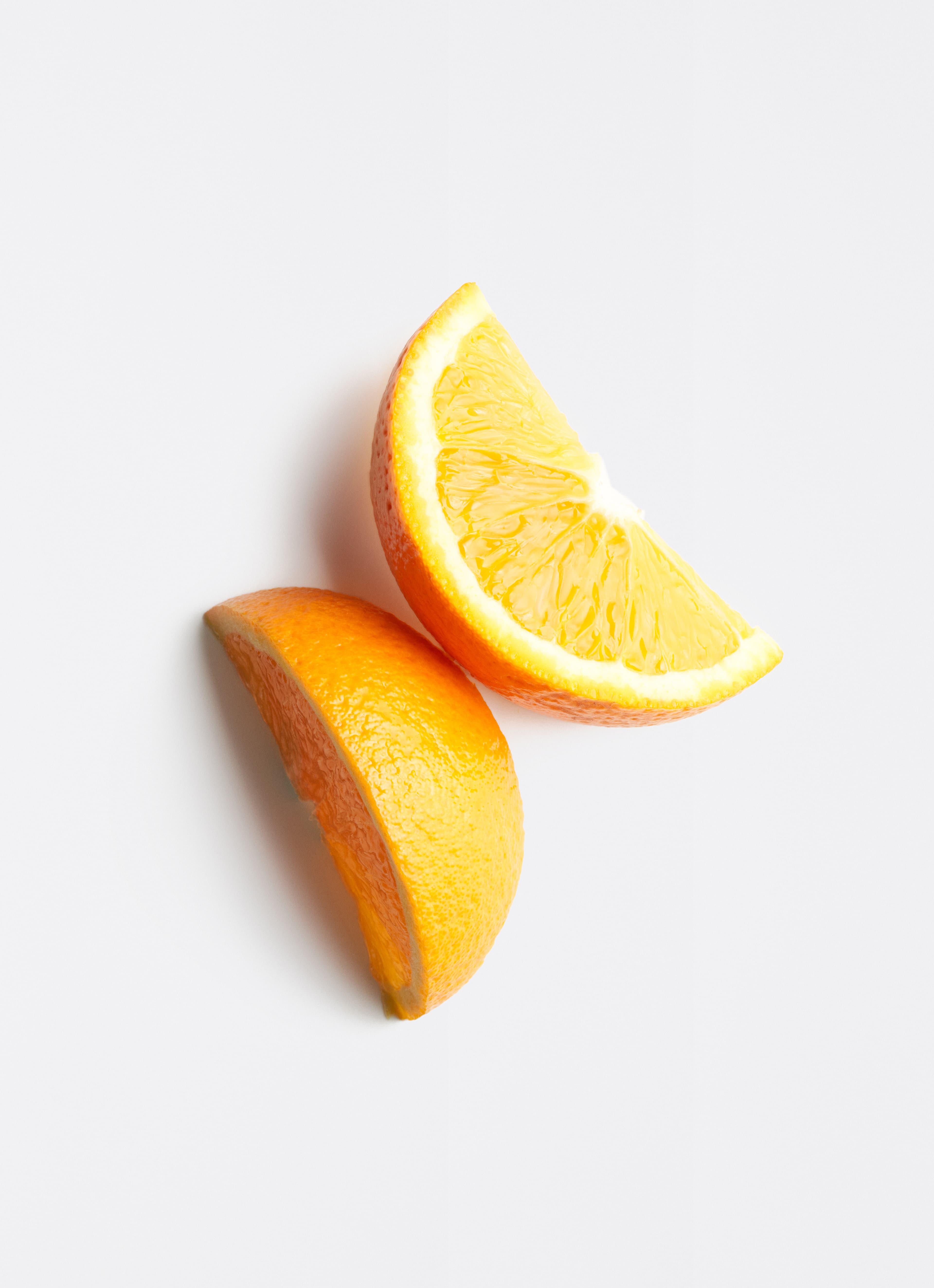 Zwei Orangenspalten auf hellgrauem Hintergrund.