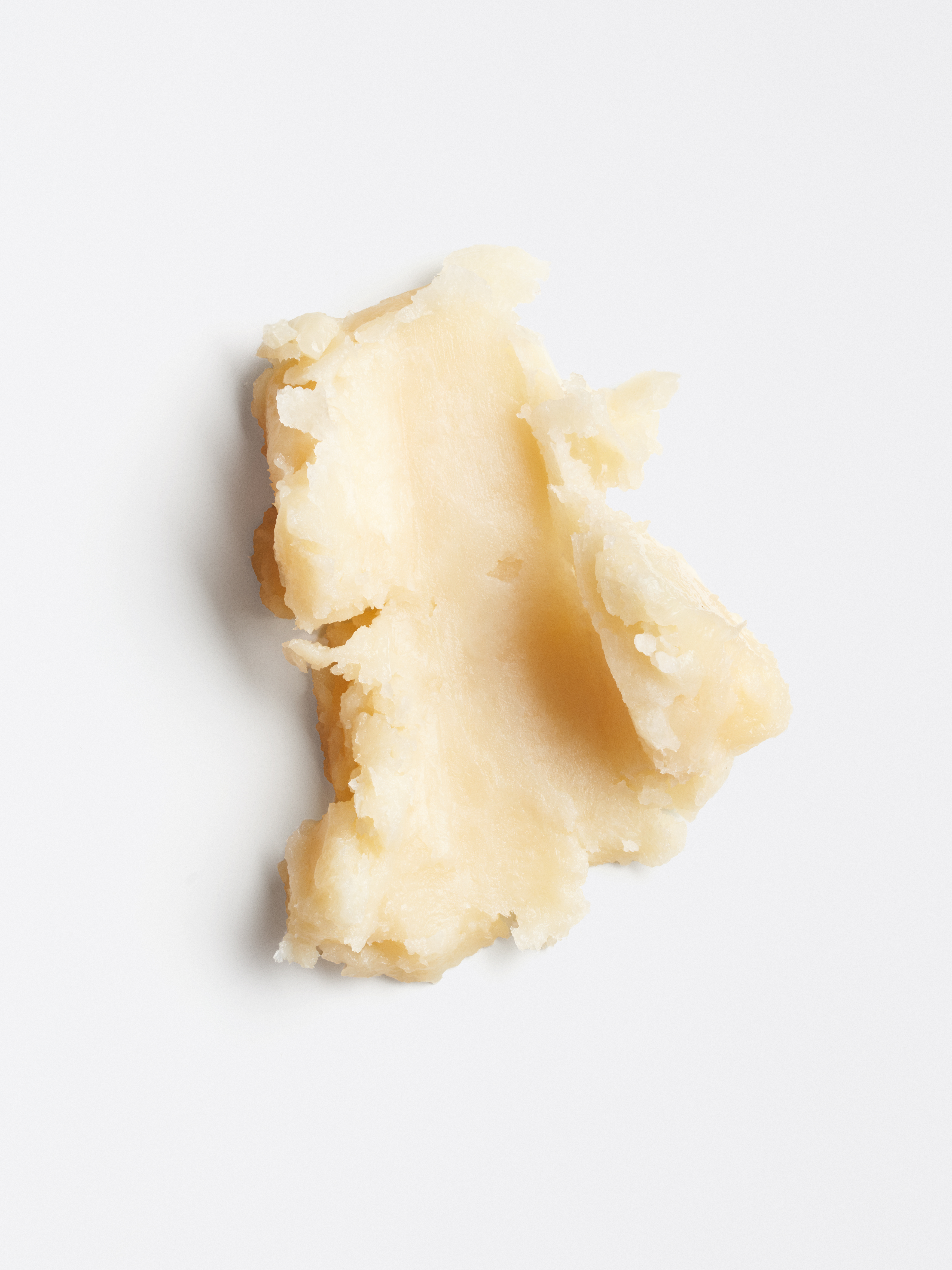Ein Stück beige-gelber Murumuru-Butter auf hellgrauem Hintergrund.