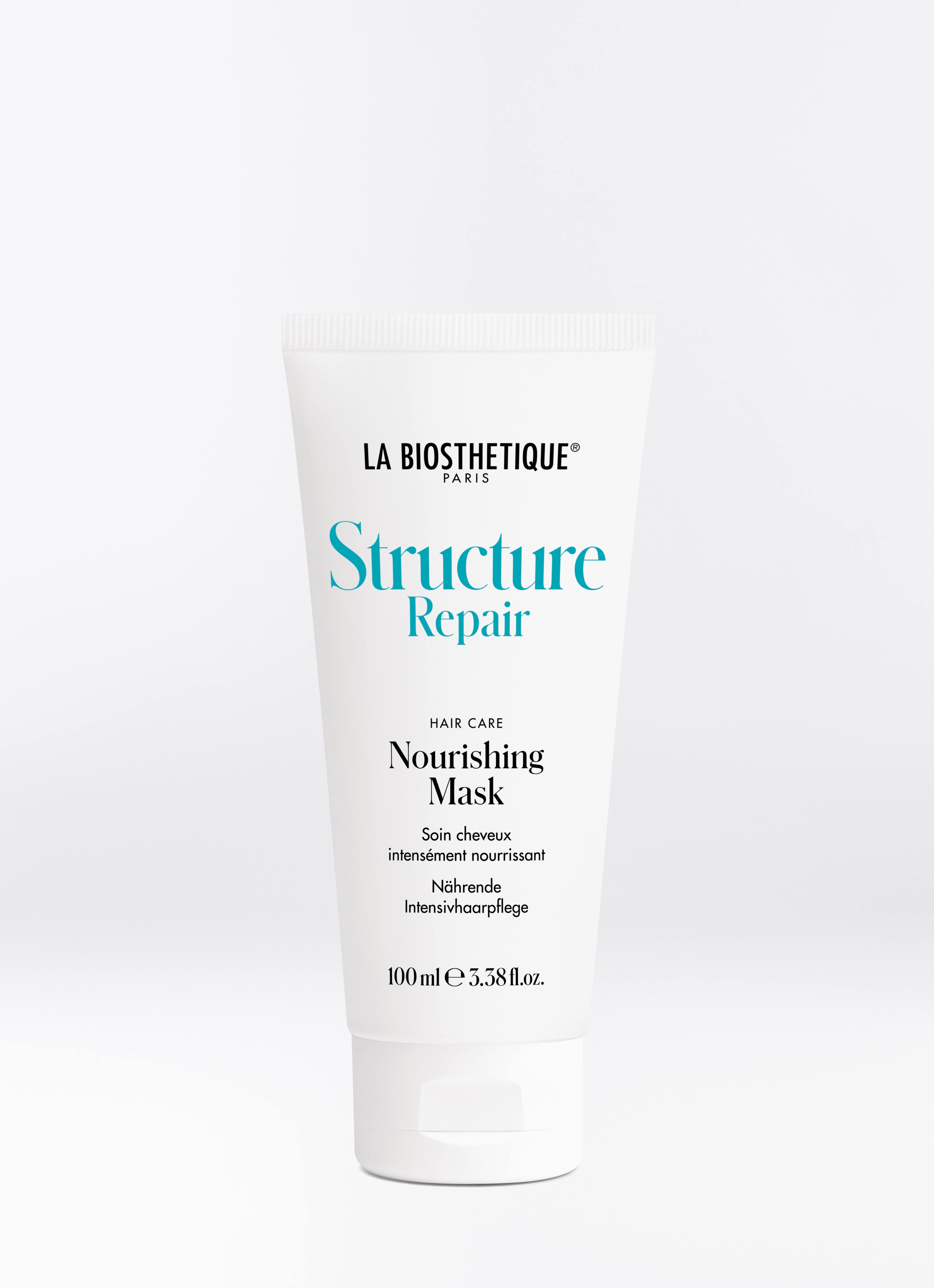 Weiße Tube der Structure Repair Nourishing Mask auf hellgrauem Hintergrund.