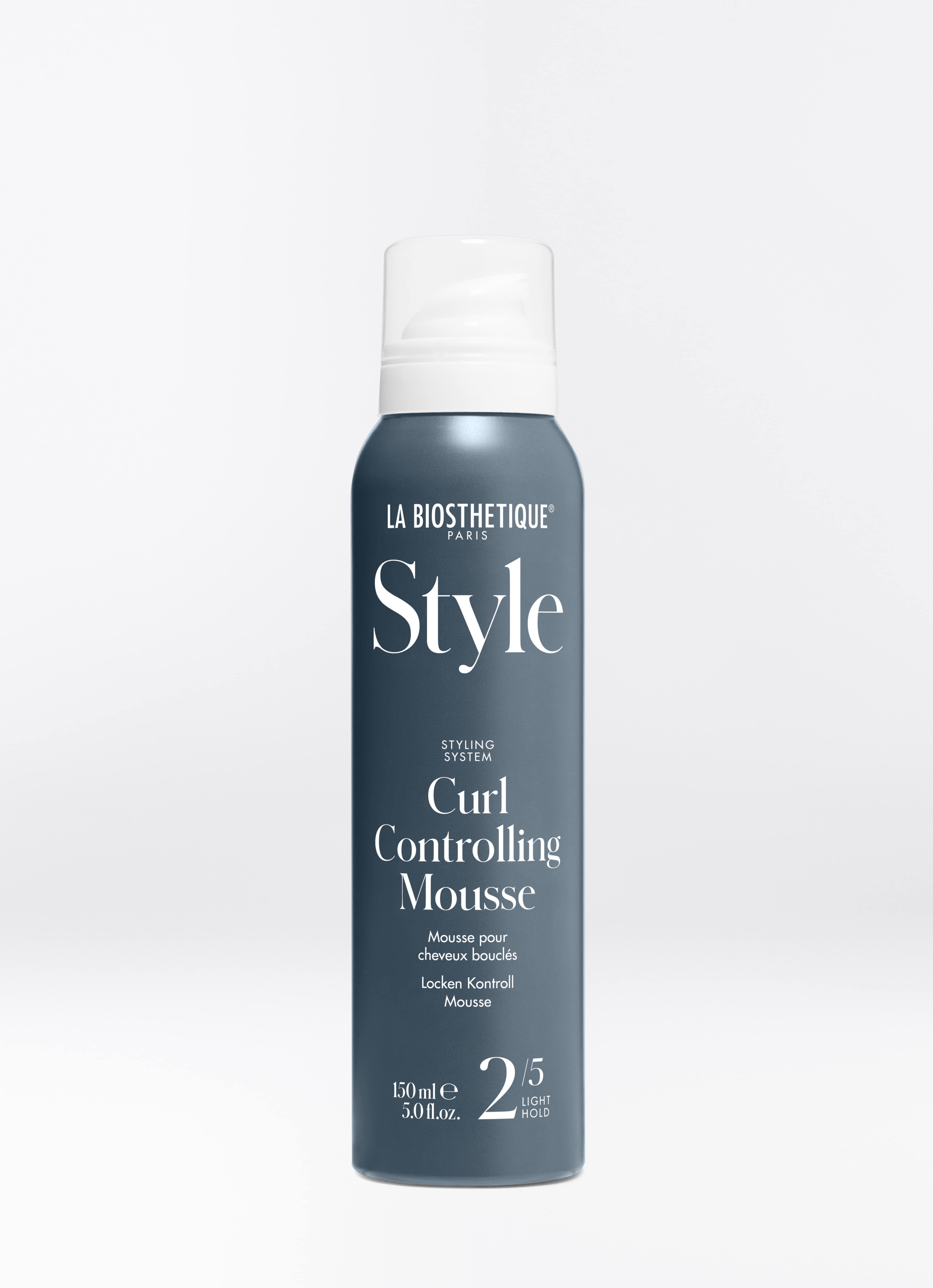 Dunkle, stahlblaue Flasche mit Schaumspender der Curl Controlling Mousse auf hellgrauem Hintergrund.