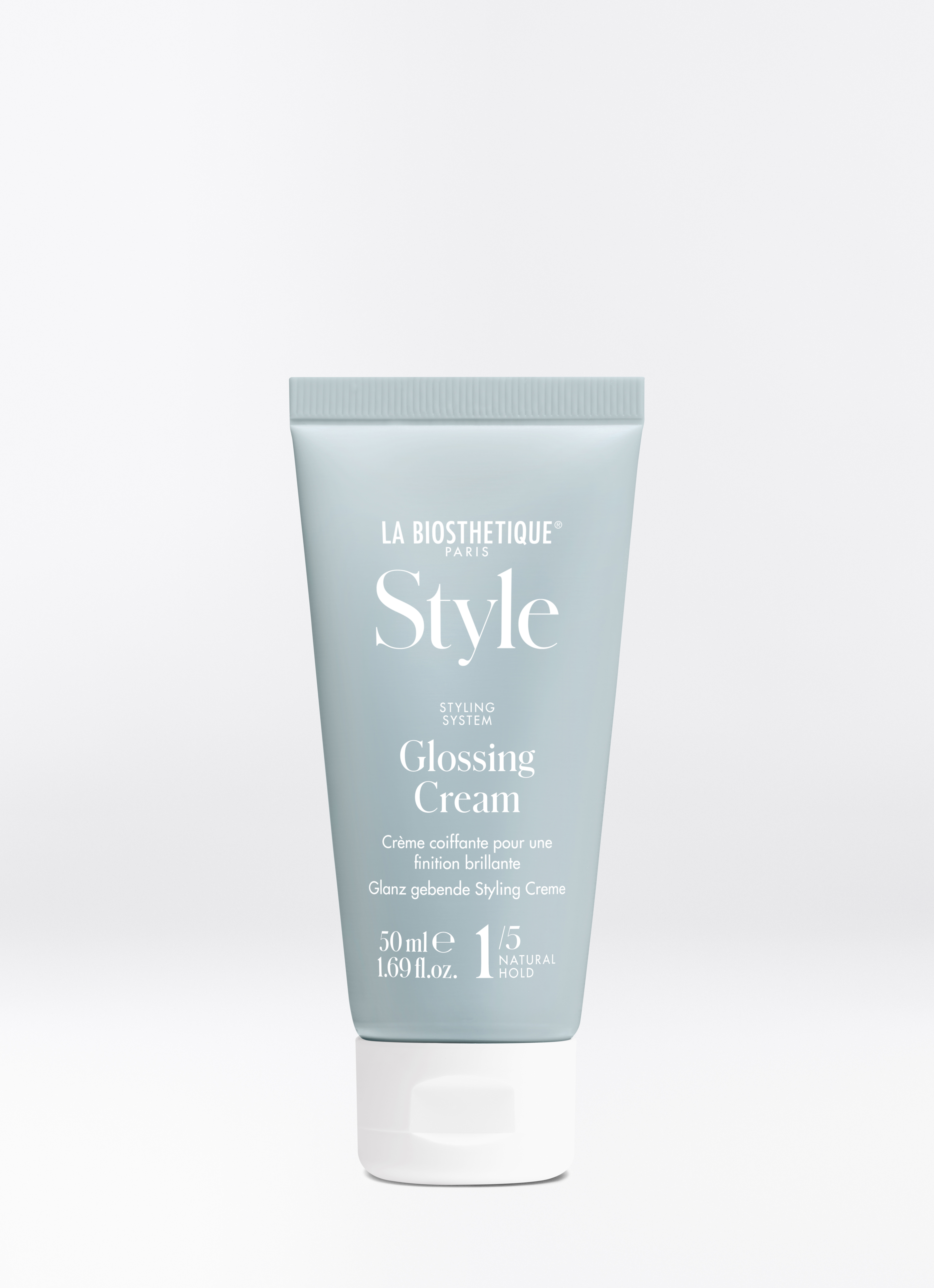 Helle, eisblaue Tube der Glossing Cream auf hellgrauem Hintergrund.